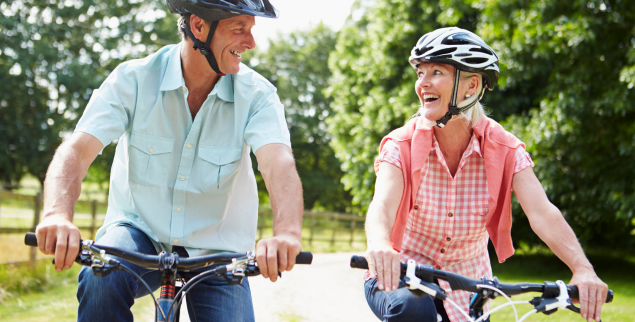 Happy couple riding bikes through the park