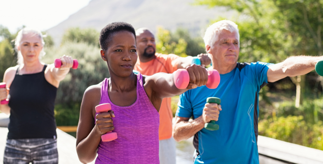 Group of people exercising outdoors with weights living healthy life